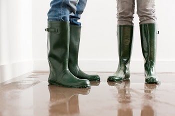 2 people wearing rubber rain boots on wet floor